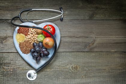 Heart shape on wooden board with fruits, grains and vegetables
